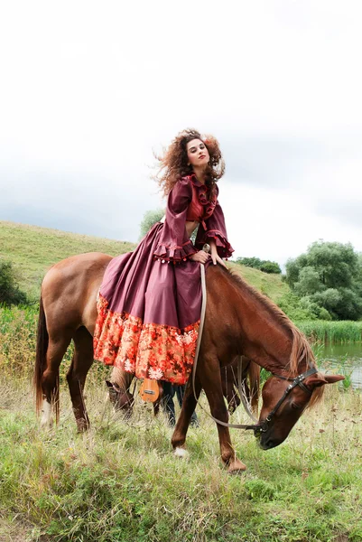 赤いドレスを着た美しいジプシーの少女。彼は馬に座っています。 — ストック写真