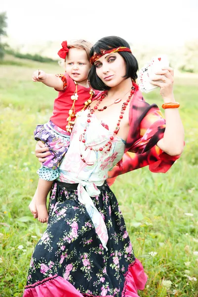 Hermosa chica gitana en un vestido rojo con el bebé. Adivina en las cartas —  Fotos de Stock