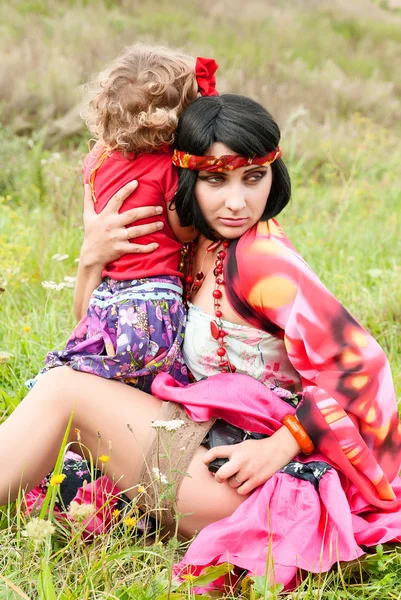 Beautiful gypsy girl in a red dress with the baby. Protect your malyshv — Stock Photo, Image