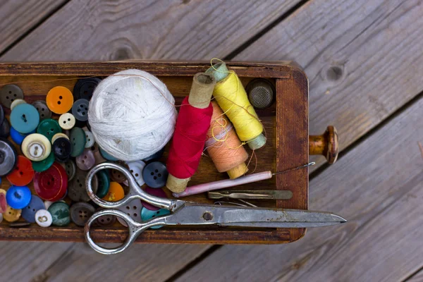 Scissors and buttons on old wooden table — Stockfoto