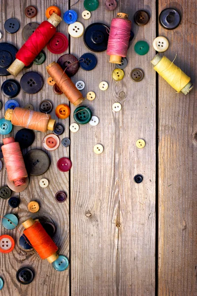 Spoelen van threads en knoppen op oude houten tafel — Stockfoto
