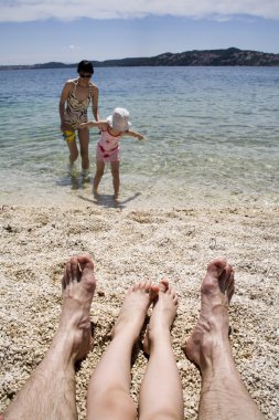 Feet of father and daughter - family on the beach clipart