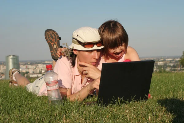 Mother and daughter at work on the notebook in park — Stock Photo, Image