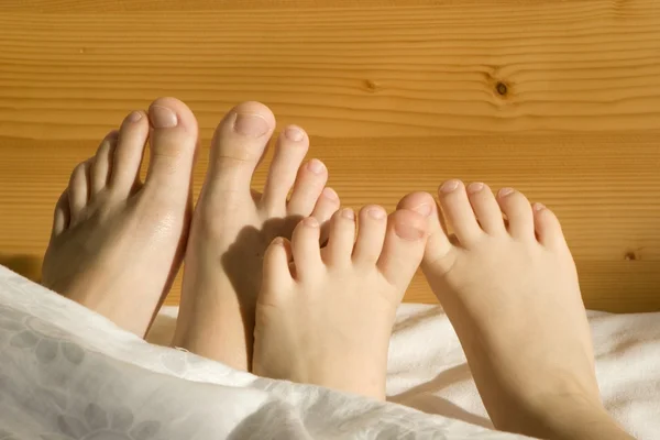 Feet of mother and child in the bed — Stock Photo, Image
