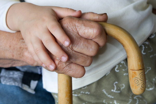 Hand of old woman and child with the staff