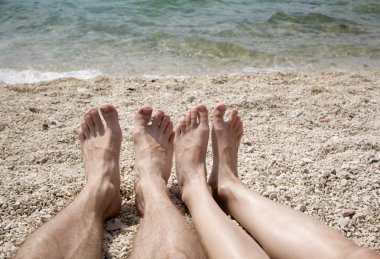 Feet of woman and man on the beach clipart