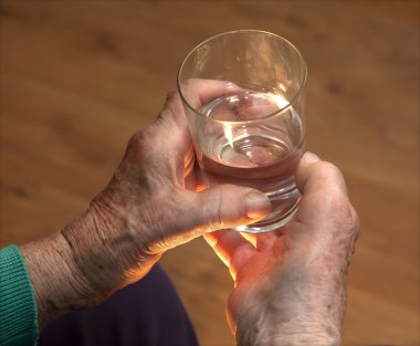 Hands of old woman and glass of water clipart