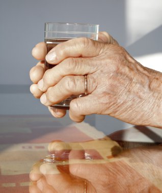 Hands of old woman and glass of water clipart