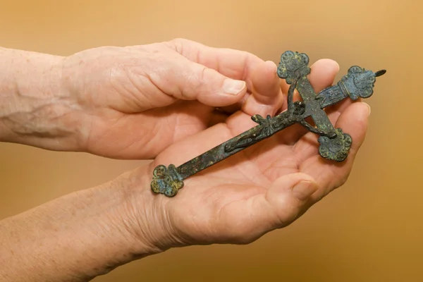 Hands of old woman and old cross — Stock Photo, Image