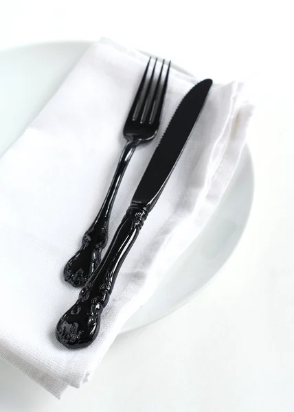 Primo piano di un coltello e una forchetta su un piatto bianco con tovagliolo — Foto Stock