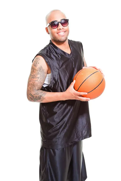篮球运动员戴着黑色太阳镜站和持有球上白色隔离室画像。他手臂上的纹身. — 图库照片