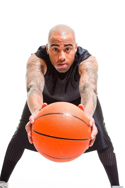 Studioporträt eines Basketballspielers, der isoliert auf weiß steht und Ball hält. Tätowierungen auf seinen Armen. — Stockfoto