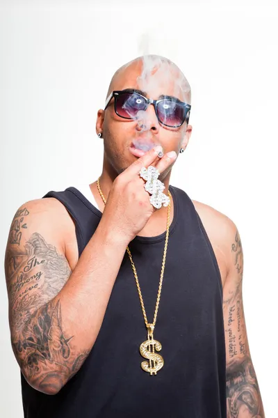 Hip hop urban gangster black man wearing dark shirt and bling bling isolated on white. Smoking cigarette. Looking confident. Cool guy. Studio shot. — Stock Photo, Image