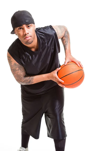 Portrait studio du joueur de basket portant une casquette noire debout et tenant la balle isolée sur blanc . — Photo