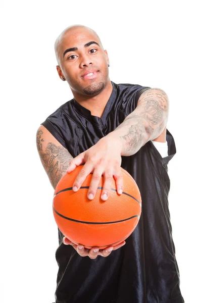 Retrato de um jovem jogador de basquete de pé com uma bola contra fundo branco. Tiro no estúdio. Tatuagens em seus braços . — Fotografia de Stock