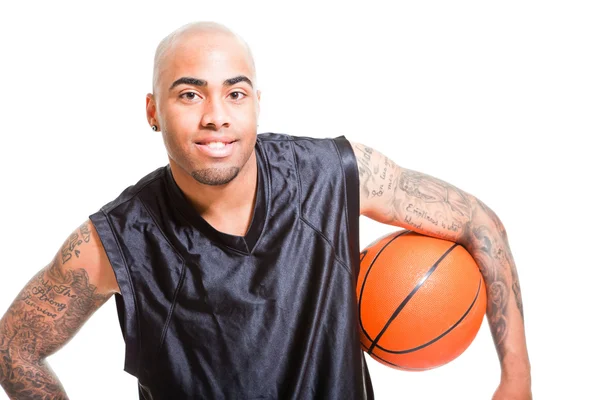 Portrait d'un jeune joueur de basket debout avec une balle sur fond blanc. Prise de vue. Tatouages sur ses bras . — Photo