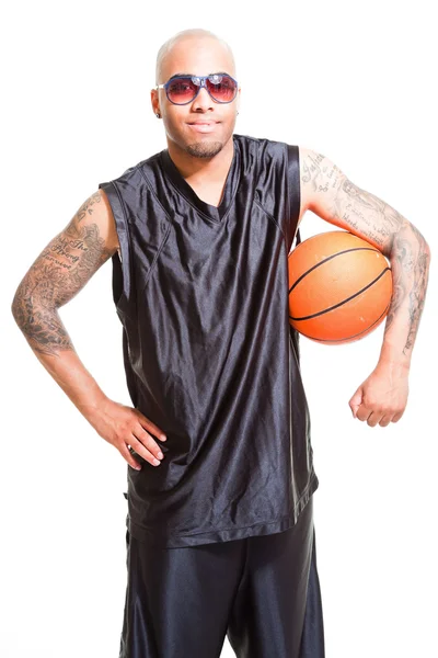 Retrato de estudio del jugador de baloncesto con gafas de sol negras de pie y sosteniendo la pelota aislada en blanco. Tatuajes en sus brazos . —  Fotos de Stock