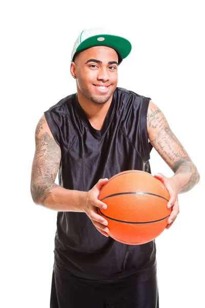 Στούντιο πορτρέτο του μπασκετμπολίστας φορώντας πράσινο καπάκι μόνιμης και κρατώντας τη μπάλα που απομονώνονται σε λευκό. τατουάζ στα χέρια του. — Φωτογραφία Αρχείου