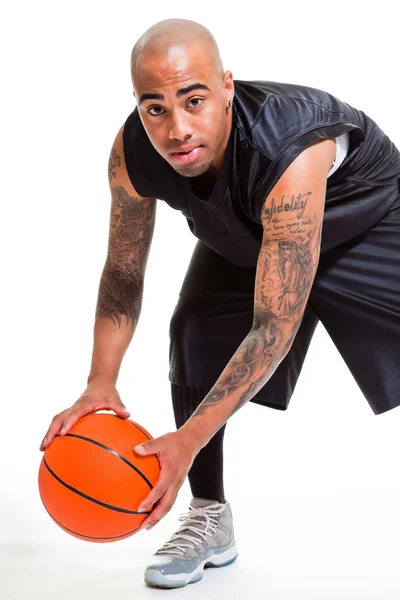 Retrato de um jovem jogador de basquete de pé com uma bola contra fundo branco. Tiro no estúdio. Tatuagens em seus braços . — Fotografia de Stock