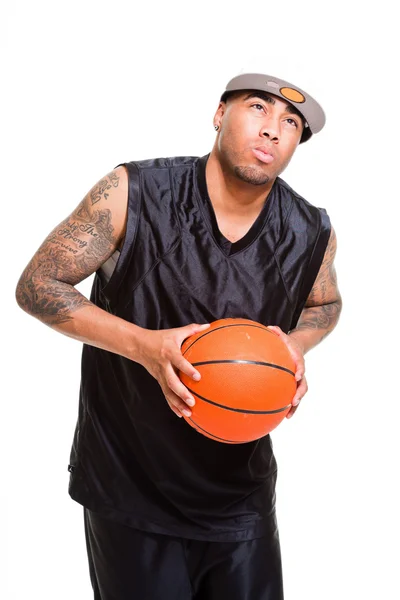 Studio portrait of basketball player wearing white cap standing and holding ball isolated on white. Tattoos on his arms. — Stock Photo, Image
