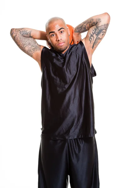 Retrato de un joven jugador de baloncesto de pie con una pelota sobre fondo blanco. Grabado en estudio. Tatuajes en sus brazos . —  Fotos de Stock