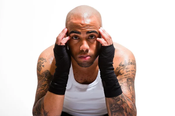 Boxeador masculino joven aislado sobre fondo blanco. Con camisa blanca y pantalones cortos negros. Equipo de entrenamiento. Piel húmeda por sudoración. Tatuajes en sus brazos . — Foto de Stock