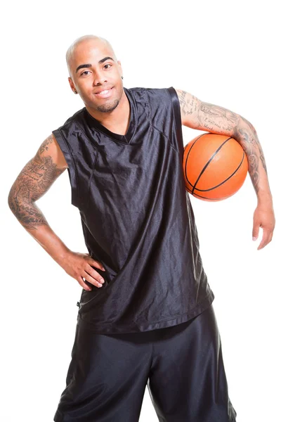 Porträt eines jungen Basketballspielers, der mit einem Ball vor weißem Hintergrund steht. Studioaufnahmen. Tätowierungen auf seinen Armen. — Stockfoto