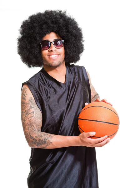 Studio portrét retro basketbalista s afro vlasy stojí a drží míč izolovaných na bílém. tetování na ruce. — Stock fotografie