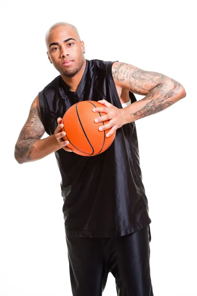 Potret seorang pemain basket muda berdiri dengan bola melawan latar belakang putih. Studio shot. Tato di lengannya . — Stok Foto