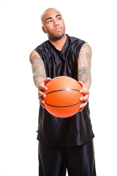Retrato de un joven jugador de baloncesto de pie con una pelota sobre fondo blanco. Grabado en estudio. Tatuajes en sus brazos . —  Fotos de Stock