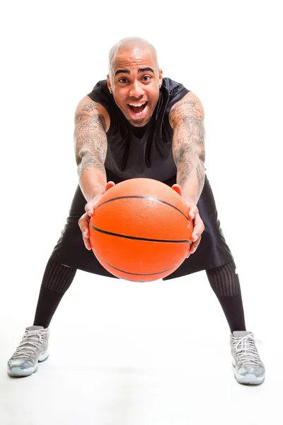 Studio portret van basketbalspeler permanent en houden bal geïsoleerd op wit. tatoeages op zijn armen. — Stockfoto