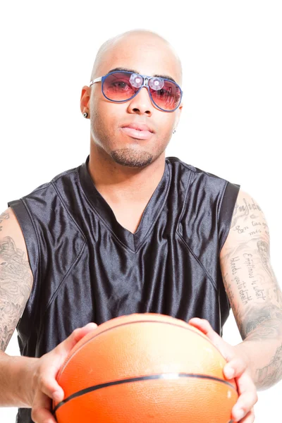 Στούντιο πορτρέτο του μπασκετμπολίστας φορώντας μαύρα γυαλιά ηλίου, στέκεται και έχει μπάλα που απομονώνονται σε λευκό. τατουάζ στα χέρια του. — Φωτογραφία Αρχείου
