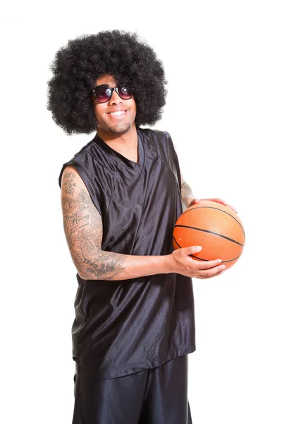 Studio portrét retro basketbalista s afro vlasy stojí a drží míč izolovaných na bílém. tetování na ruce. — Stock fotografie
