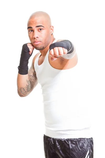 Boxeador masculino joven aislado sobre fondo blanco. Con camisa blanca y pantalones cortos negros. Equipo de entrenamiento. Piel húmeda por sudoración. Tatuajes en sus brazos . —  Fotos de Stock