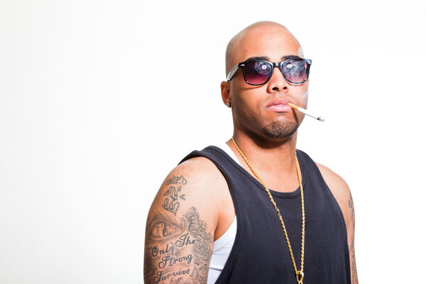 Хип-хоп городской гангстер черный мужчина в темной рубашке и блеск изолированы на белом. Курю сигарету. Выглядишь уверенно. Крутой парень. Снимок студии
.