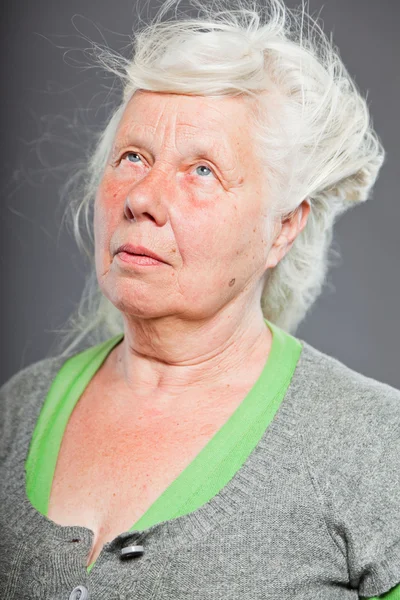 Studiový portrét šťastný starší ženy s dlouhými vlasy ve větru. Studio záběr izolované na šedém pozadí. — Stock fotografie