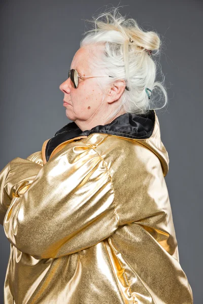 Cool senior kvinna bär gyllene jacka. lång grå hår. solglasögon. Studio skott. isolerade. — Stockfoto