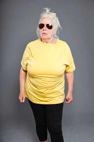 Cool hip senior woman with sunglasses and long grey hair. Expressive face. Studio shot isolated on grey. — Stock Photo, Image