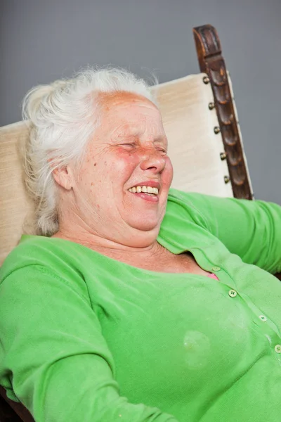 Mulher sênior relaxado feliz com cabelos longos cinza sentado na cadeira. Estúdio tiro isolado em fundo cinza . — Fotografia de Stock