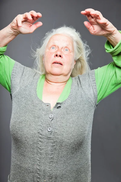 Mujer mayor pelo gris blanco haciendo poses espirituales. Cara y manos expresivas. Estudio plano aislado sobre fondo gris . — Foto de Stock