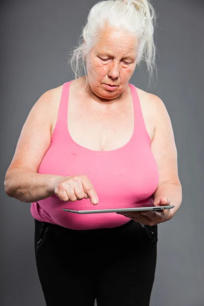 Donna anziana in possesso di tablet lunghi capelli grigi. Colpo in studio. Isolato su sfondo grigio . — Foto Stock