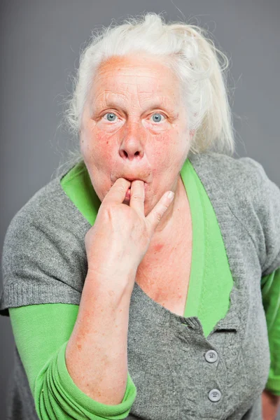 Donna anziana che fischia con le dita. Si comporta da giovane. Studio girato isolato su sfondo grigio . — Foto Stock