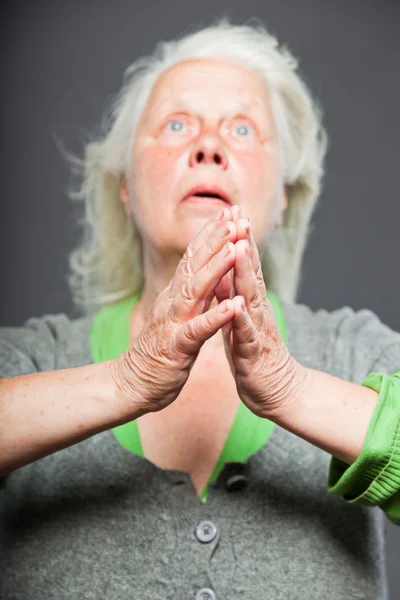 Senior woman white grey hair doing spiritual poses. Expressive face and hands. Studio shot isolated on grey background. — Stock Photo, Image