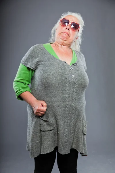 Femme âgée portant des lunettes de soleil au visage expressif. C'est drôle. Studio tourné isolé sur fond gris . — Photo