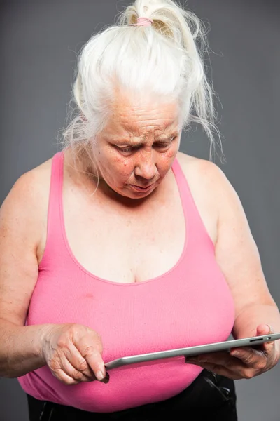 タブレットの灰色の長い髪を保持している年配の女性。スタジオ ショットします。灰色の背景上に分離されて. — ストック写真