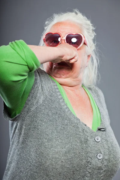 Mujer mayor con gafas de sol con cara expresiva. Qué curioso. Estudio plano aislado sobre fondo gris . —  Fotos de Stock