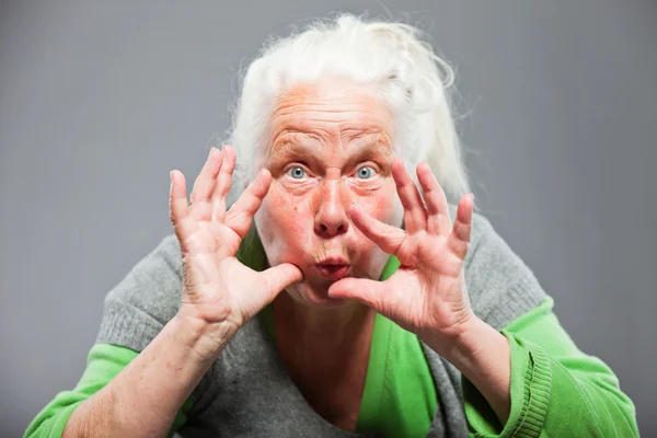 Śmieszne kobieta starszy ekspresji. działając młodych. Studio strzał na białym tle na szarym tle. — Zdjęcie stockowe