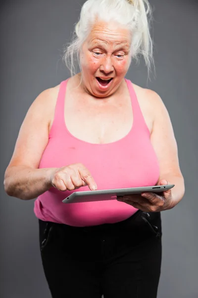 Femme âgée tenant un comprimé longs cheveux gris. Prise de vue. Isolé sur fond gris . — Photo