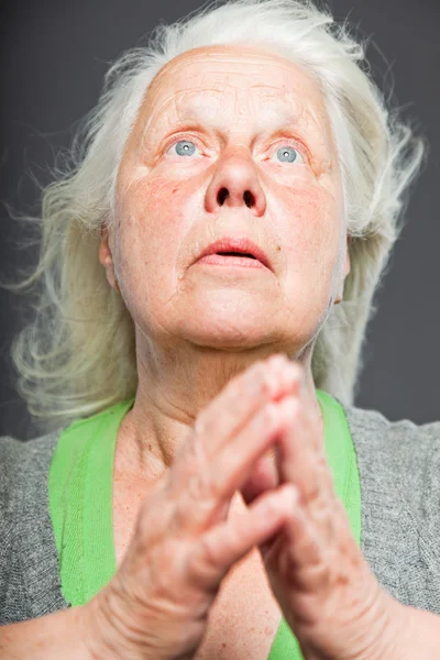 Senior vrouw wit grijs haar doen spirituele vormt. expressief gezicht en handen. studio opname geïsoleerd op grijze achtergrond. — Stockfoto