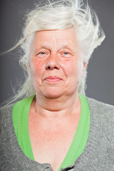 Studio portrait of happy senior woman with long hair in the wind. Studio shot isolated on grey background. — Stock Photo, Image